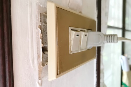 electric receptacle partially hanging from wall